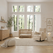 The Cove beige nursery recliner in a bright nursery beside a wooden crib and side table